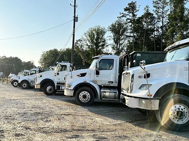 A row of white SSR roll-off trucks parked in the yard
