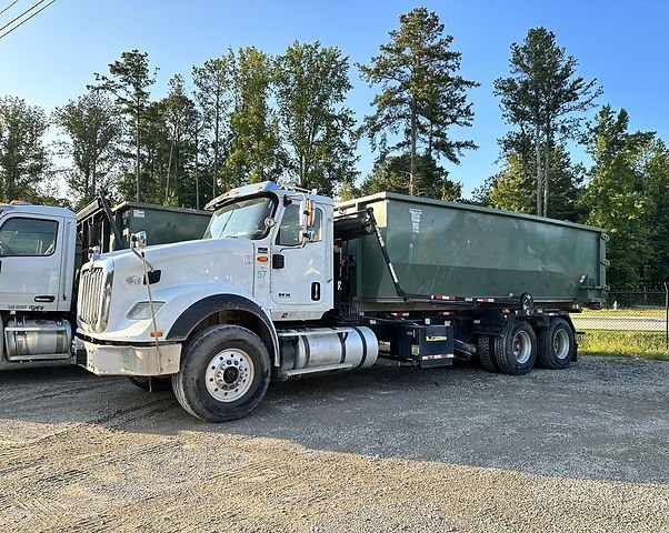 SSR roll-off truck carrying a green roll-off container